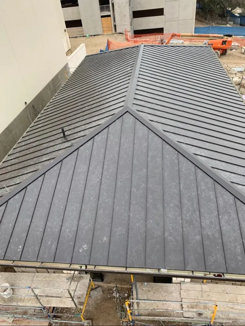 Commercial metal roof construction with crane equipment in Newton